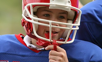 Young boy with sportsguard wearing football helmet