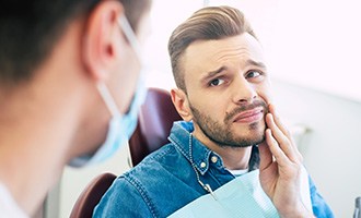 Patient holding cheek needing root canal treatment