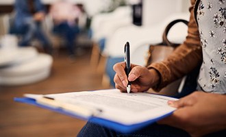 Woman filling out forms on blue clipboard