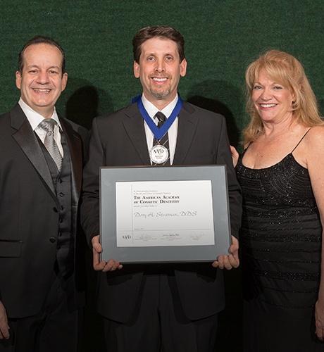 Massapequa Park dentist holding award certificate from the American Academy of Cosmetic Dentistry