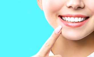 person pointing at her cosmetic dentistry smile in Massapequa Park