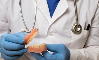 dentist holding dentures in hand