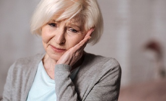 Senior woman experiencing pain due to dental implant failure in Massapequa Park, NY