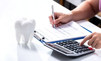 Tooth, calculator, and pen and paper on desk