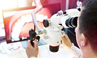 dentist using surgical microscope for dental implants in Massapequa Park