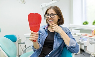 young woman admiring her new dental implants in Massapequa Park 