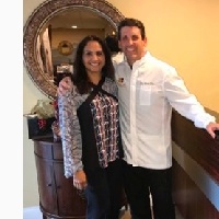 Dentists smiling in front of reception desk in Massapequa Park dental office