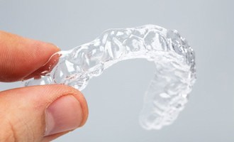 A person holding a clear aligner.