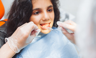 Dentist putting clear aligner on teenage girl