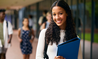 Teenage girl smiling while holding blue binder