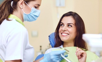 A woman smiling in the dentist’s chair at her dental hygienist