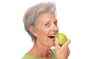 older woman smiling holding apple