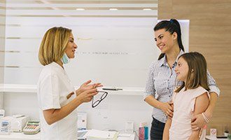 mom and daughter talking to dentist