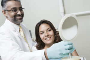 Dentist holding mirror with patient