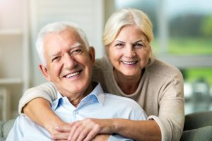 an elderly couple hugging and smiling after seeing an emergency dentist in Massapequa