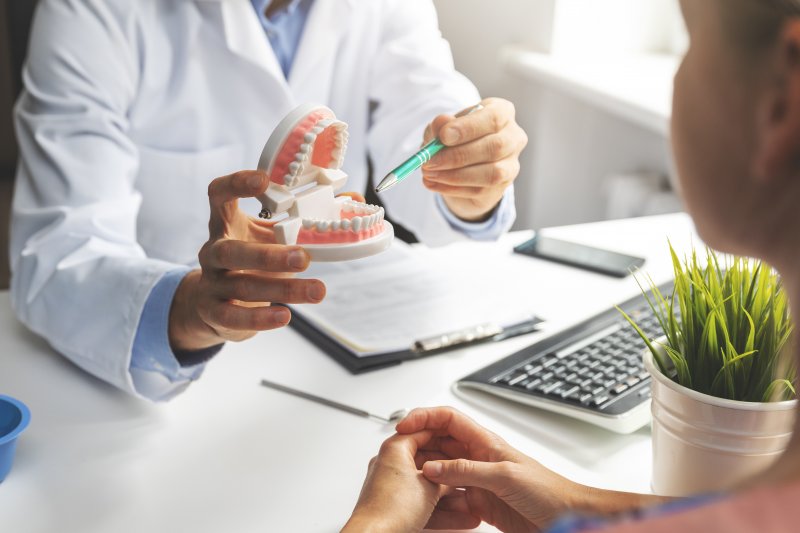 Dentist pointing to model of teeth in office