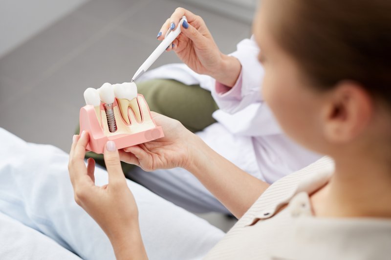 a dentist showing a patient a dental implant in Massapequa Park