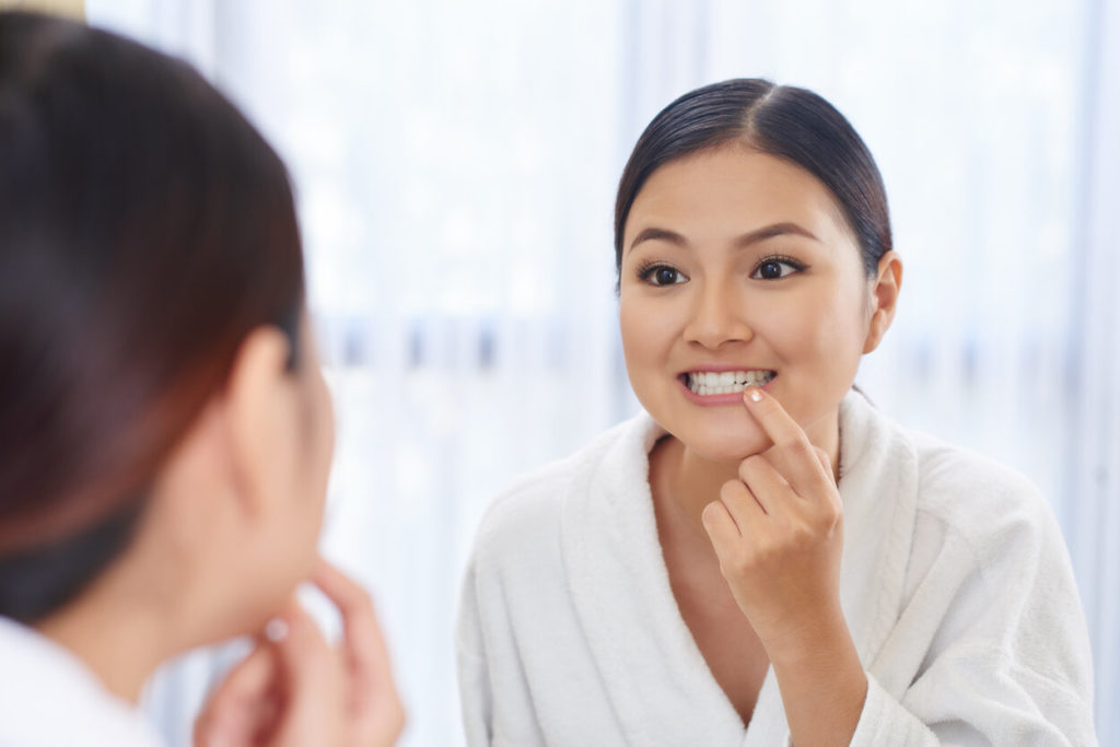 person checking their teeth in a mirror