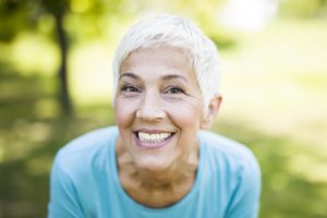 senior woman grinning with dental implants in Massapequa
