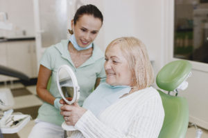 Older woman in dentist’s chair looking in mirror