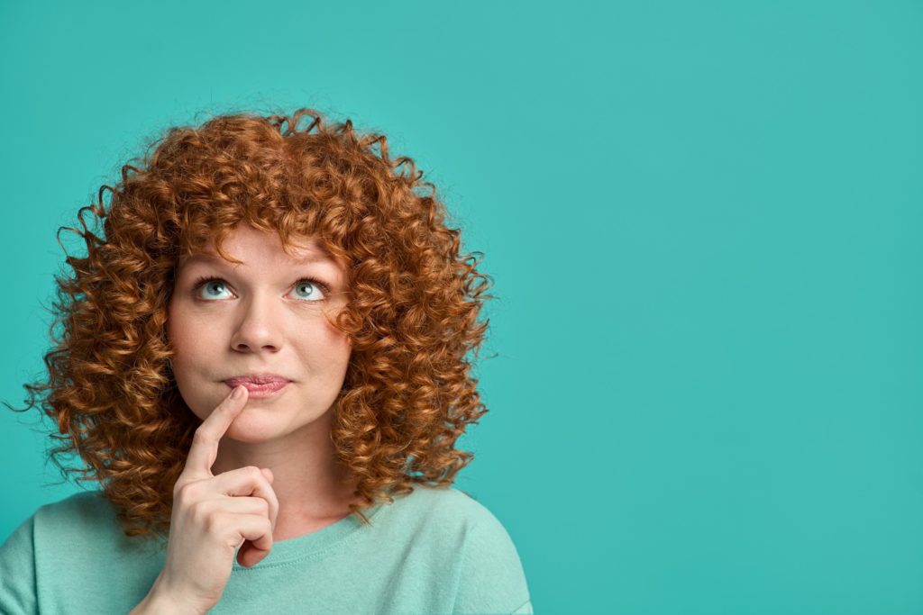 Woman with red, curly hair wondering