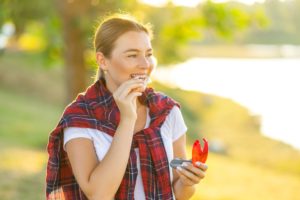 Woman outside in the sun inserting clear aligner tray