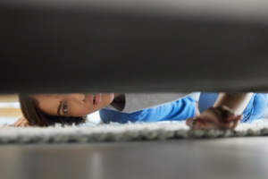 Woman looking underneath her couch for Invisalign aligners