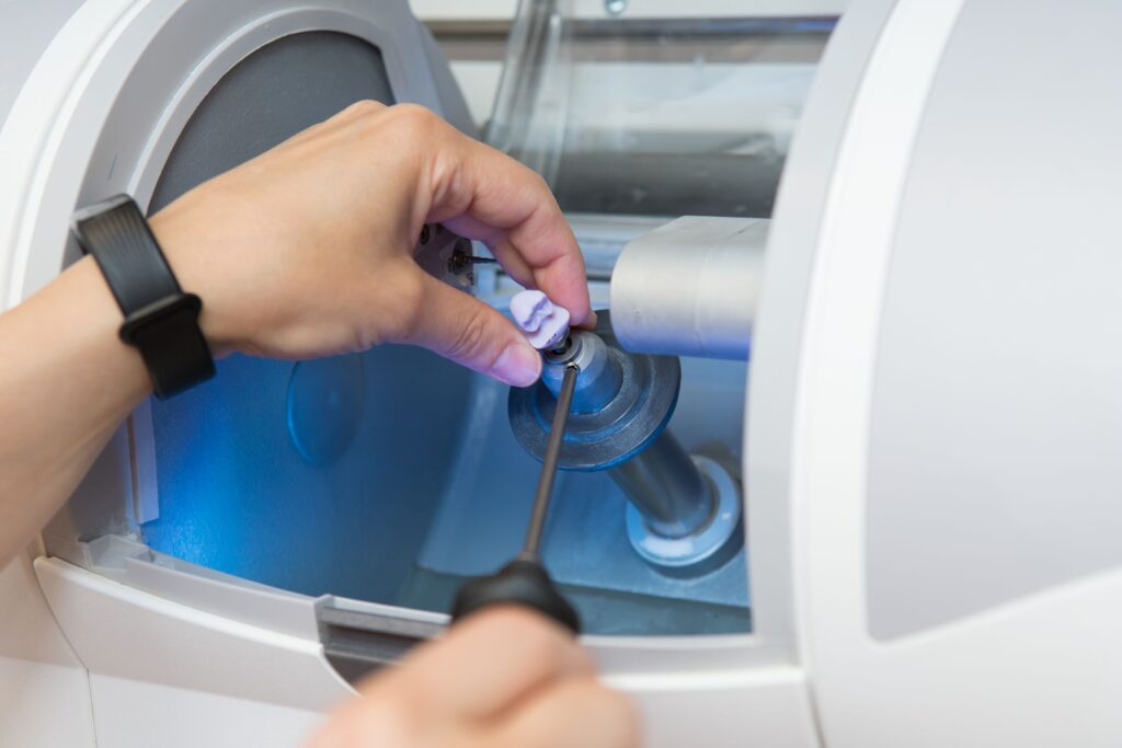 Hands removing CEREC crown from milling machine